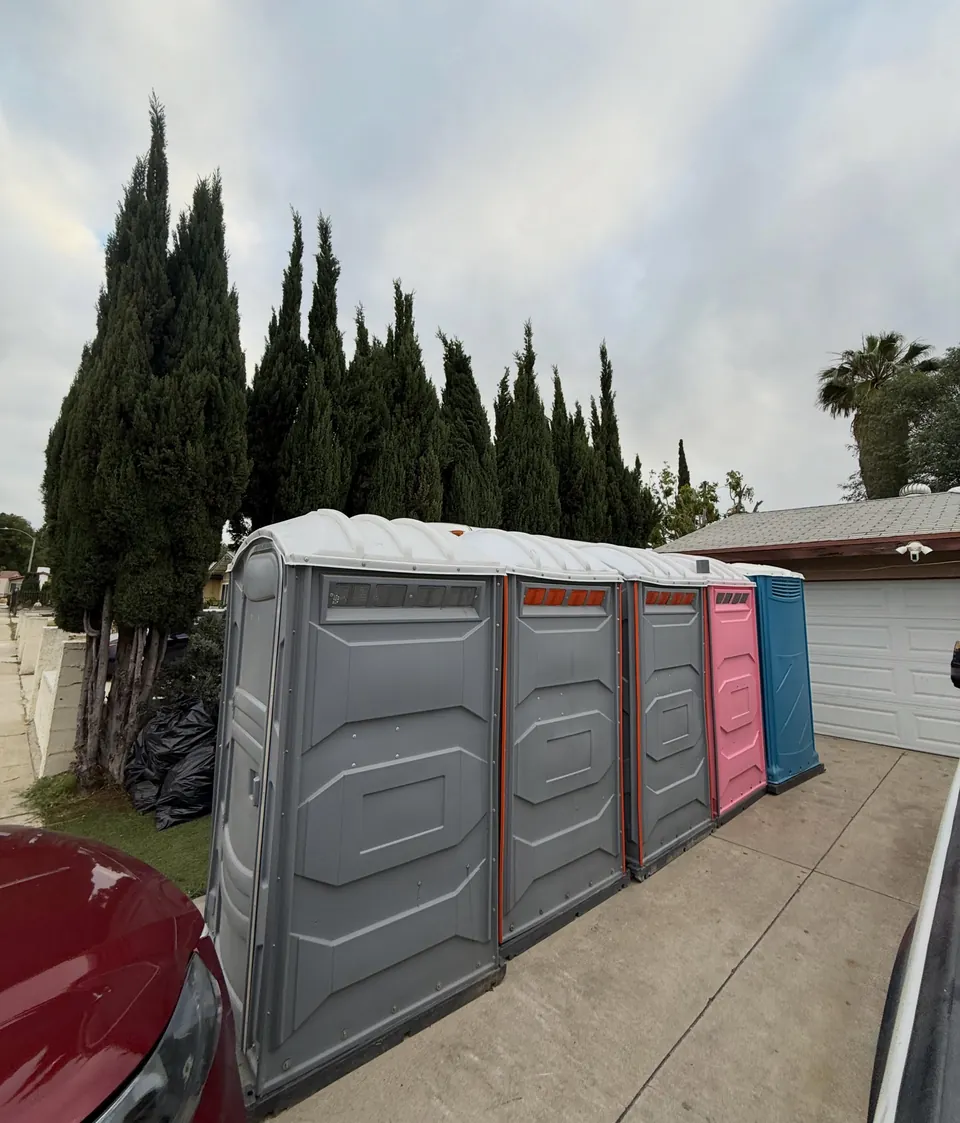 Wide gray portable restroom beside a row of standard units